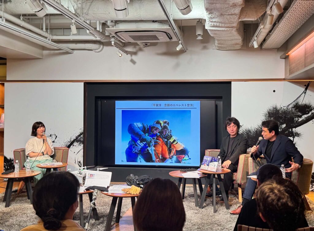 『親友は山に消えた』刊行記念トークイベントで、スクリーンに山岳写真を映しながら登壇者が観客に向けて語りかけている様子